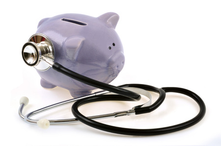 Stethoscope resting on a piggy bank on a white backgroundの写真素材