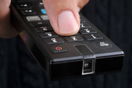 Close-up on a TV remote control in hand