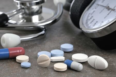 Mix of drugs in front of a stethoscope and a blood pressure monitorの写真素材