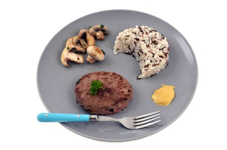 Chopped steak with rice and mushrooms served on a plateの写真素材