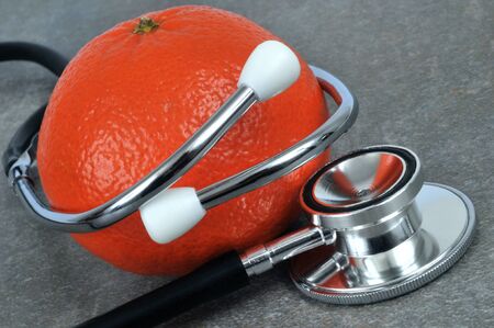 Stethoscope and tangerine close-up on gray backgroundの写真素材