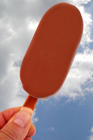 Iced stick coated with chocolate close-up on cloudy sky backgroundの写真素材