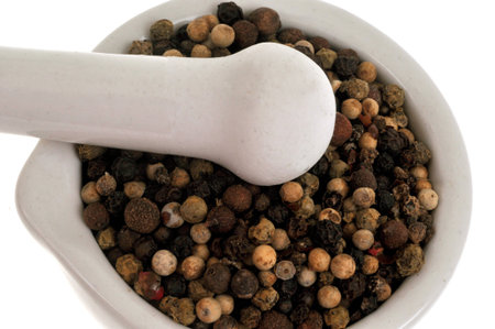 Peppercorns in a mortar with pestle close-up on a white background