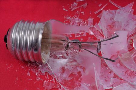 Broken electric bulb close up on red backgroundの写真素材