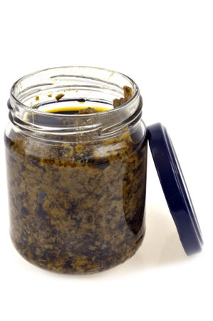 Jar of pesto sauce opened close up on white background