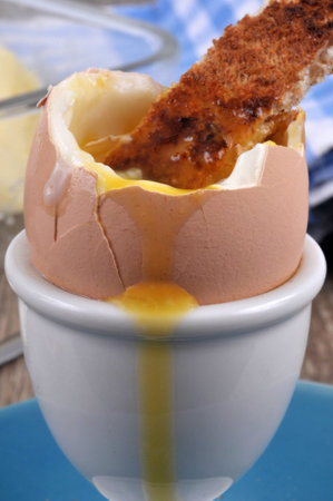 Soft-boiled egg in its egg cup with a piece of toasted bread