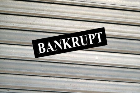 Paper with bankruptcy written glued to a closed store blindの写真素材