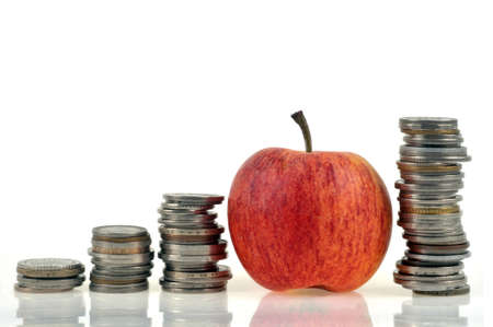 Apple surrounded by stacks of coins on white backgroundの写真素材