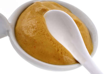 Ramekin of mustard with a spoon close-up on white backgroundの写真素材