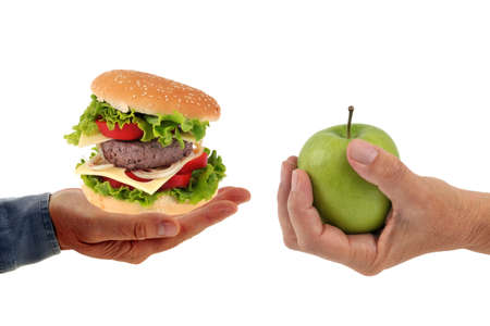 Hamburger in one hand and Granny Smith apple in the other hand on white backgroundの写真素材
