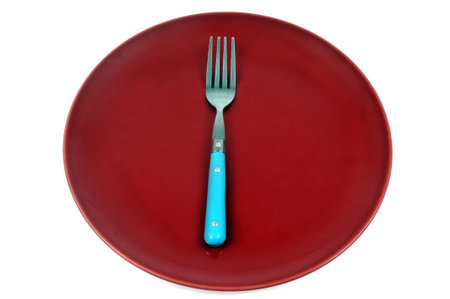 Fork in a red plate close-up on white backgroundの写真素材