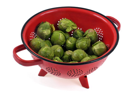 Colander of raw Brussels sprouts close-up on white backgroundの写真素材