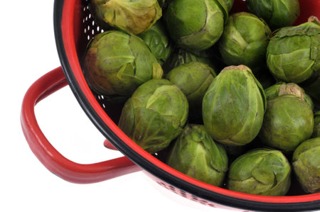 Colander of raw Brussels sprouts close-up on white backgroundの写真素材