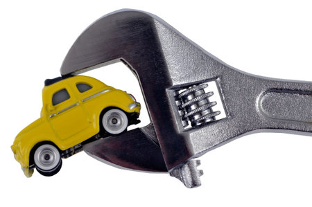 Mechanics concept with a car held by an adjustable wrench close-up on a white backgroundの写真素材