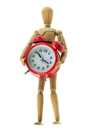 Wooden articulated mannequin wearing an alarm clock close-up on white backgroundの写真素材