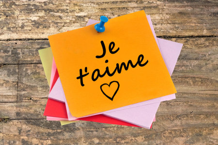 I love you written in french on a piece of paper on a wooden backgroundの写真素材