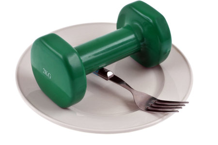 Dumbbell and fork in a plate close-up on white backgroundの写真素材