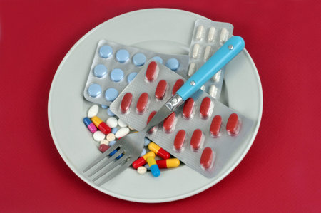 Food and vitamin supplements in a plate with a fork on a red background