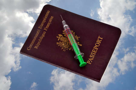 Vaccine syringe lying on a European passport close-up on cloudy sky backgroundの写真素材