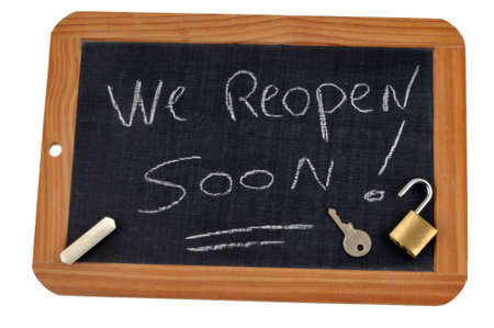 We reopen soon written on a school slate with chalk and an open padlock