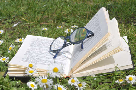 Open book with glasses in the grassの写真素材