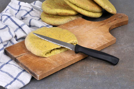 Pita bread cut on a cutting board with a knife close-up on a gray backgroundの写真素材