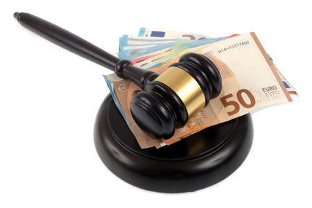 Judge's gavel resting on its plinth with a wad of euro banknotes close-up on a white backgroundの写真素材