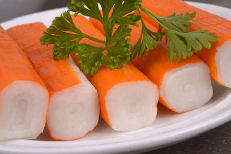 Surimi sticks in a saucer with a sprig of parsley close-upの写真素材