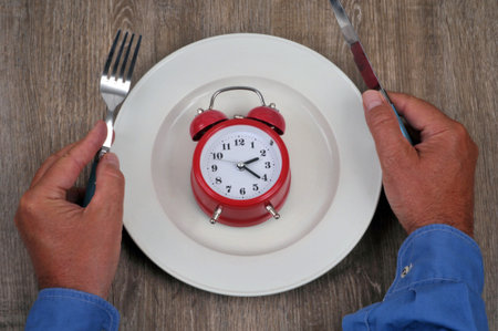 Mealtime concept with an alarm clock on a plate