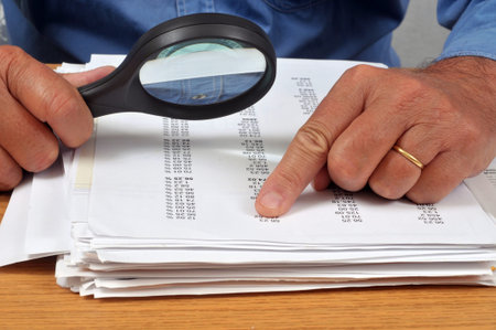 Man checking a list of numbers with a magnifying glass