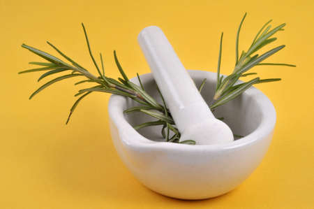 Sprigs of rosemary in a mortar with a pestle close-up on a yellow backgroundの写真素材