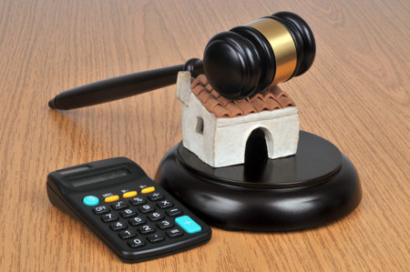 Concept of estimating a house with an auctioneer hammer and a calculator on wooden background