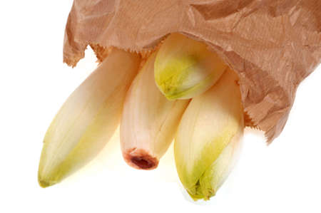 Fresh and organic endives coming out of a paper bag close-up on white backgroundの写真素材
