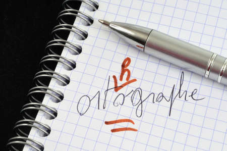 The word spelling written in french and corrected on a spiral notebook with a pen close-upの写真素材
