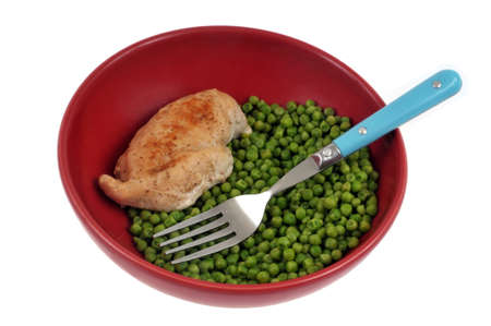 Plate of peas with a chicken breast and a fork on white backgroundの写真素材