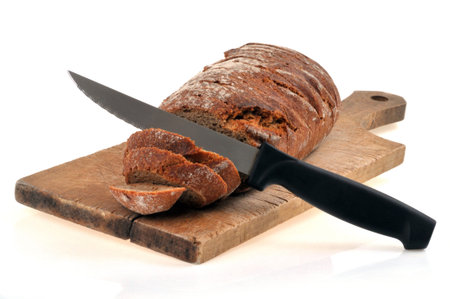 Sliced rye bread with a knife on a cutting board on a white background