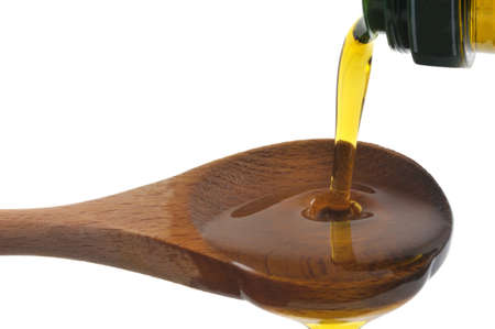 Pouring olive oil into a wooden spoon close-up on a white backgroundの写真素材