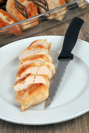 Cooked chicken breast cut in a plate with a knifeの写真素材