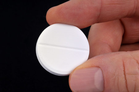 Effervescent aspirin pill held in hand close up on black background