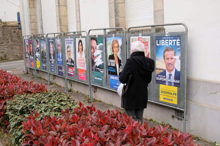 Woman from the back passing in front of the posters of the candidates for the French presidential electionのeditorial素材