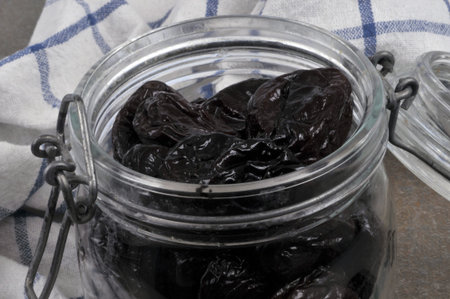 Open jar of prunes with a tea towel close-up