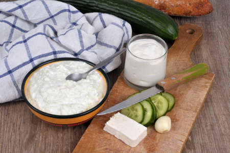 Ramekin of homemade tzatzÃ­ki with its ingredients placed on a cutting boardの写真素材