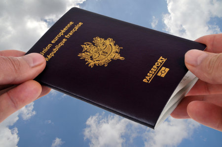 A passport exchange from hand to hand close up against a cloudy sky backgroundの写真素材