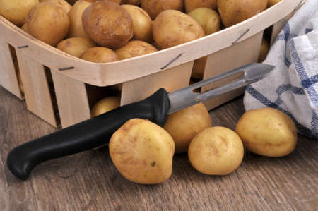 Wooden crate of potatoes with a vegetable peelerの写真素材