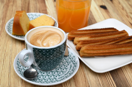 Cup of coffee with a plate of churros and a glass of orange juiceの写真素材