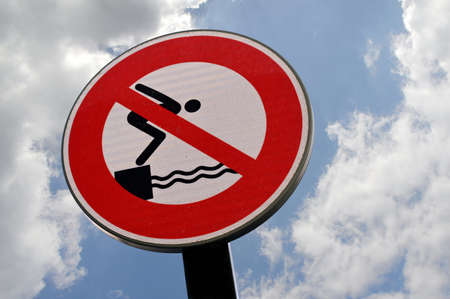 Warning sign prohibiting diving and swimmingの写真素材