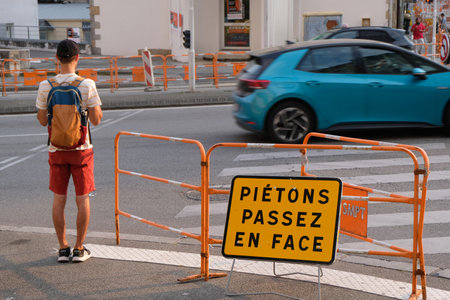 Traffic sign directing pedestrians to change sidewalks in french in front of a pedestrian crossingのeditorial素材