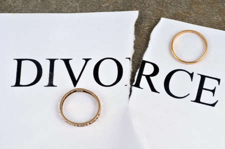 Divorce concept with torn sheet of paper and wedding ringsの写真素材