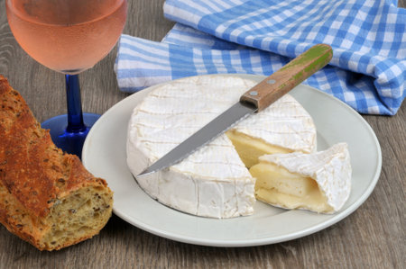 Started camembert on a plate with a glass of wine and breadの写真素材