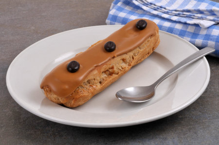 A coffee eclair in a plate with a spoon